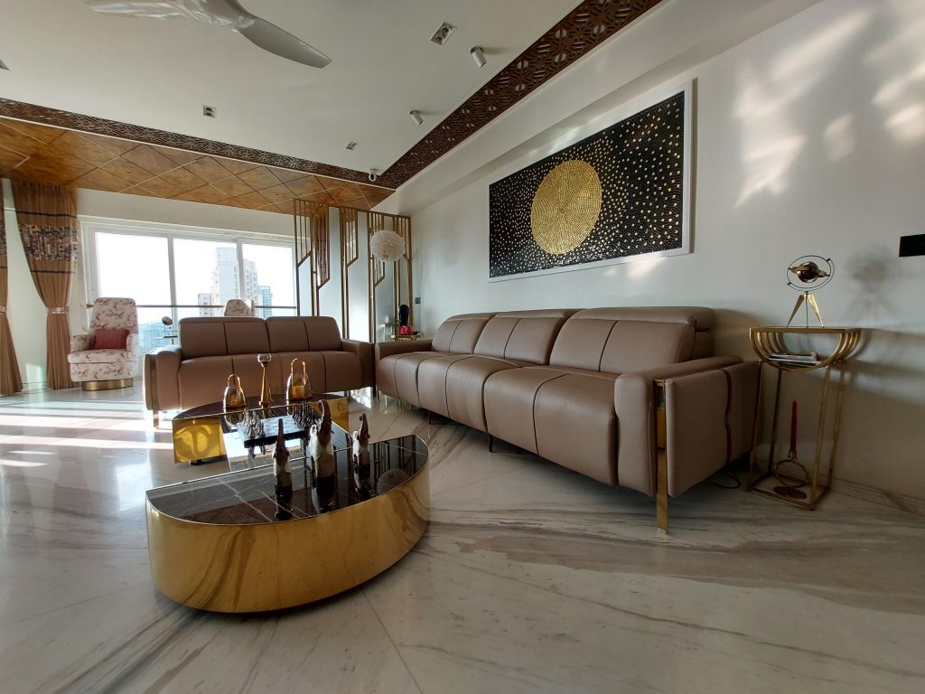 A Parisian-inspired living room with pastel colors, gold accents, plush velvet seating, and elegant drapery in a 3BHK residence.